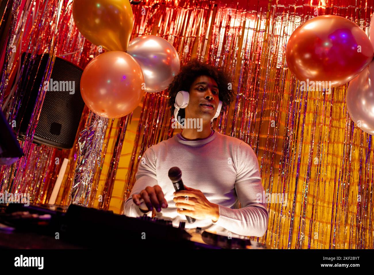 Afro americano maschio dj in cuffie che suonano musica e tenendo il microfono in un nightclub Foto Stock