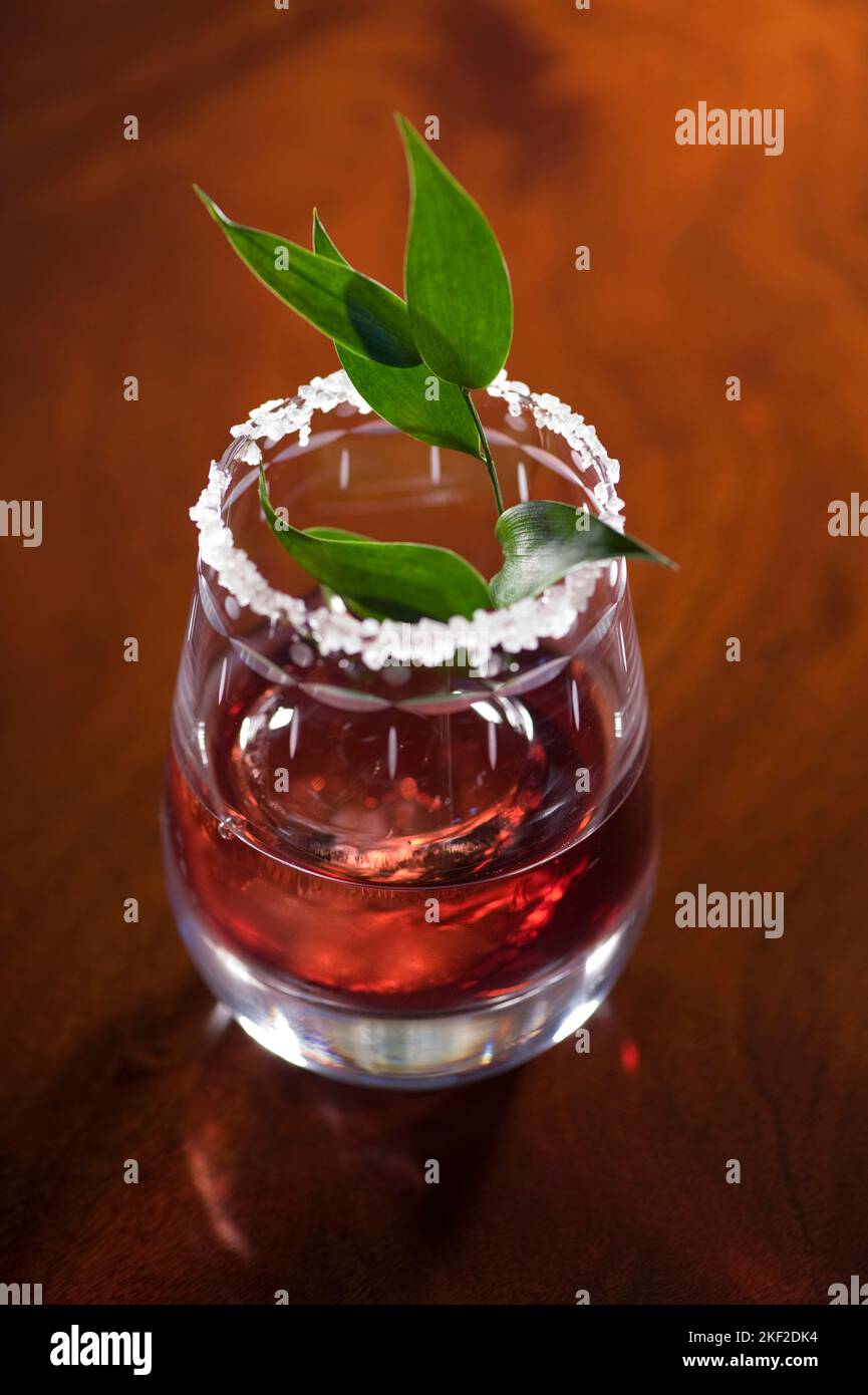 Bevanda rossa servita con foglia verde in un bicchiere guarnito. Foto Stock
