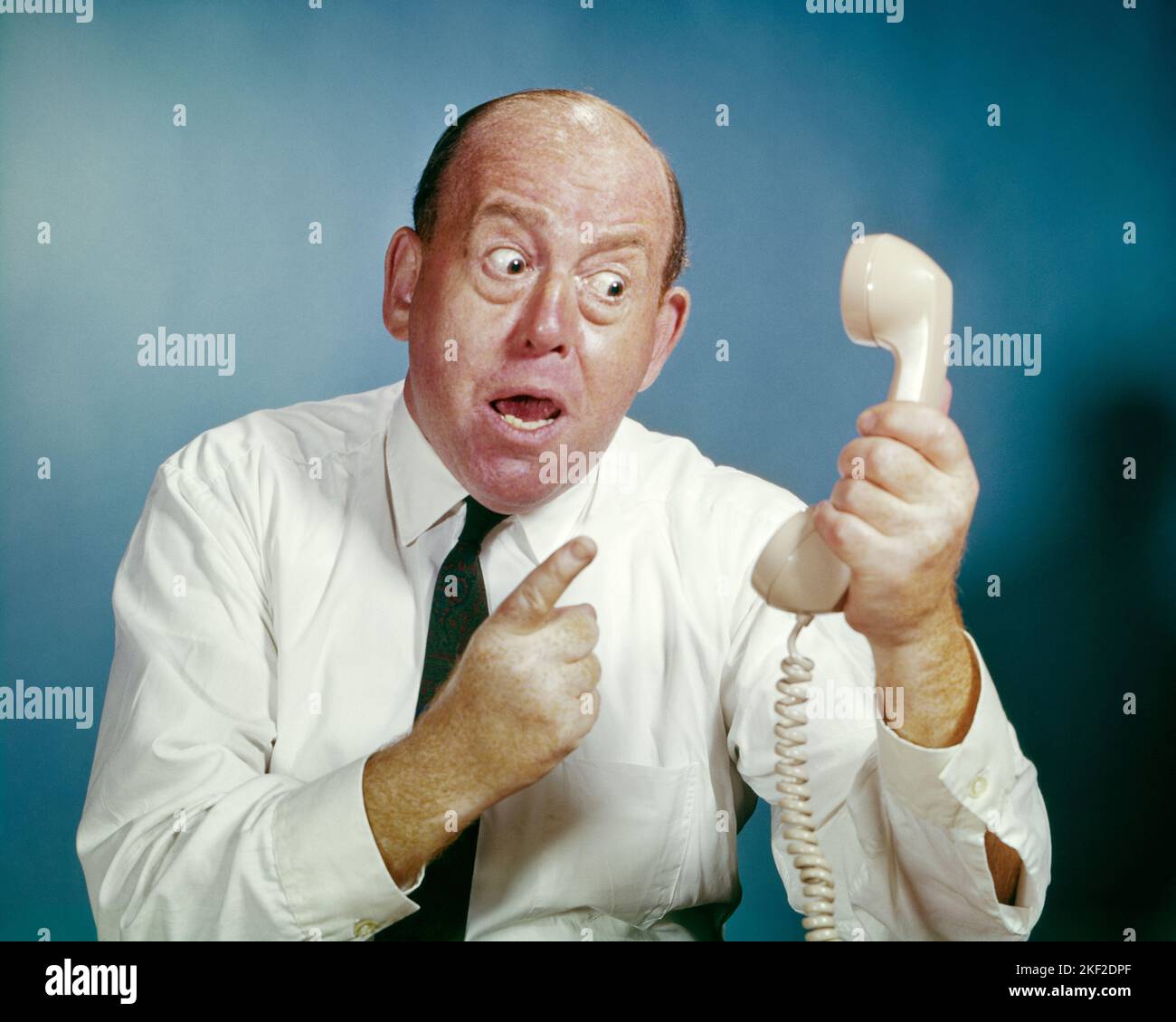 1960S UOMO ARRABBIATO CHE STA PUNTANDO E FISSANDO IL RICEVITORE DEL TELEFONO MENTRE LO TIENE LONTANO DALLA FACCIA DELL'HS - KP1327 HAR001 HARS STUDIO SHOT HOME VITA COMUNICANTE MANAGER COPIA SPAZIO PERSONE DI MEZZA LUNGHEZZA LONTANO PERSONAGGIO MASCHI DIRIGENTI GESTURING MEDIO-ETÀ LARGA UOMO DI MEZZA ETÀ BUG-EYED VENDERE STARING ANGOSCIATO SERVIZIO CLIENTI IRATE BALDING ED ECCITAZIONE AUTORITÀ GESTI OCCUPAZIONI TELEFONI BOSS CONNESSIONE CONCETTUALE INFURIATO TELEFONI RICEVITORE DISPIACERI OSTILITÀ INDIGNANTE FASTIDIO GRANDEYED EMOZIONE EMOTIVO ESASPERATO FURIOSO TIENE IRRITATO MANAGER VENDITORI SOLUZIONI STARTLED Foto Stock