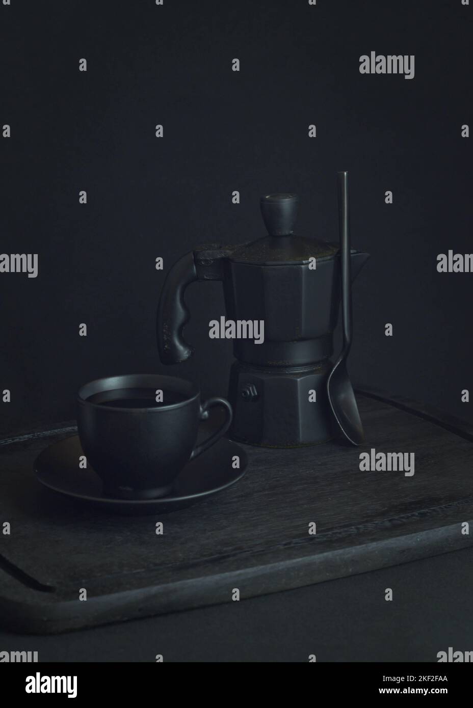 Caffè italiano. Tazza di espresso caldo, moka pot su un asse di legno rustico, sfondo scuro, messa a fuoco selettiva. Natura morta, fotografia scura. Foto Stock