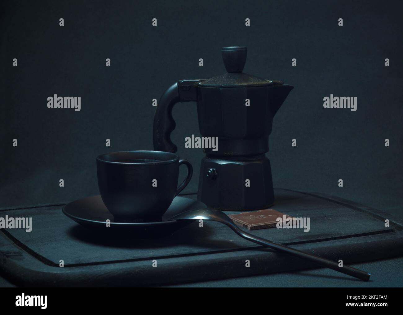 Caffè italiano. Tazza di espresso caldo, moka pot su un asse di legno rustico, sfondo scuro, messa a fuoco selettiva. Natura morta, fotografia scura. Foto Stock