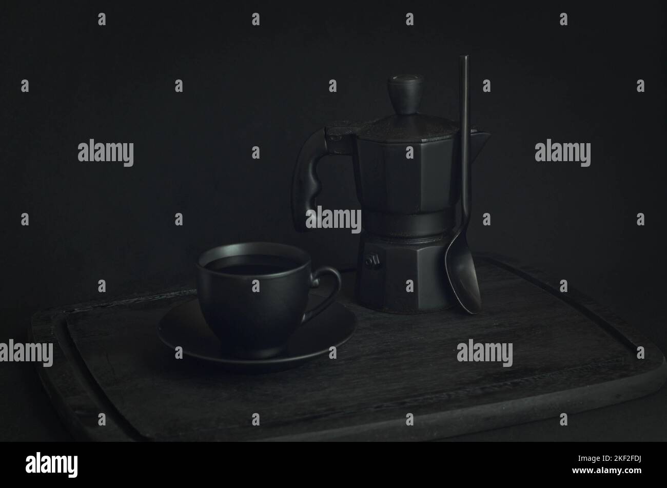 Caffè italiano. Tazza di espresso caldo, moka pot su un asse di legno rustico, sfondo scuro, messa a fuoco selettiva. Natura morta, fotografia scura. Foto Stock