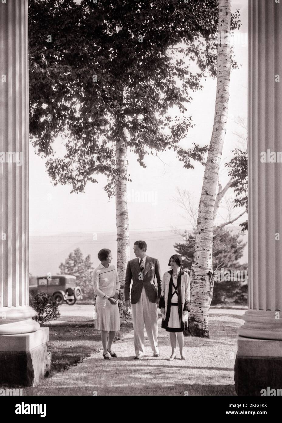 1920S 1930S UN UOMO CON DUE DONNE CHE CAMMINANO ATTRAVERSO COLONNE INGRESSO ELEGANTE VESTITO ALLA MODA - O4550 HAR001 HARS COMUNICAZIONE CANADA AMICO GIOVANE ADULTO RICCO VACANZA MISTERO RICCO STILE DI VITA STORIA FEMMINE RURALE HOME VITA LUSSO COPIA SPAZIO AMICIZIA FULL-LENGTH SIGNORE PERSONE MASCHI FIDUCIA B & W SUCCESSO TEMPO OFF TUTA E CRAVATTA FELICITÀ STILI DI SVAGO VIAGGIO FUGA RICCHEZZA COLONNE VACANZE LUSSO CONCETTUALE FASHIONABLY ABITI ELEGANTI E BENESTANTI UOMO MEDIO-ADULTO DONNA MID-ADULTA MUSKOKA VACANZE TOGETHERNESS BENE-A-FARE GIOVANE UOMO ADULTO GIOVANE DONNA ADULTO NERO E BIANCO Foto Stock