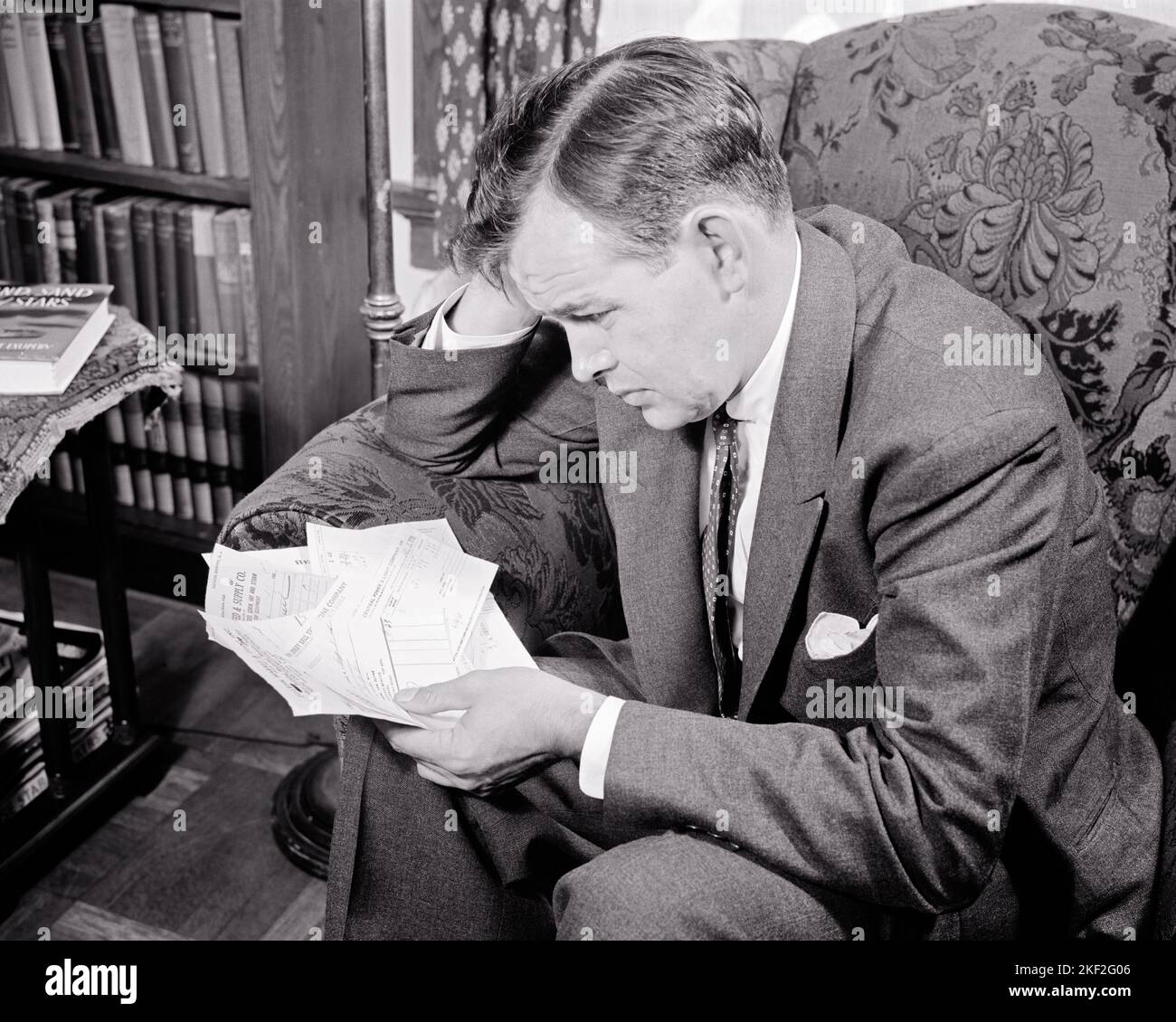 1940S UOMO PREOCCUPATO SEDUTO IN SEDIA IMBOTTITA IN POSSESSO DI DIVERSI PENDING FATTURE NON PAGATI VESTITO E CRAVATTA - S10509 HAR001 HARS FINANZE COPIA SPAZIO MEZZA LUNGHEZZA PERSONE CHE SI PREOCCUPANO MASCHI DISTURBATI B & W INTERESSATO FINANZIARIA TRISTEZZA VESTITO E CRAVATTA VENDITA AD ALTO ANGOLO DI SCOPERTA E. PREOCCUPAZIONE UMORE GLUM NON PAGATO PENDING METÀ-ADULTO MEDIO-ADULTO UOMO MISERABILE VENDITORI DIVERSI NERO E BIANCO CAUCASICO ETNICITÀ HAR001 VECCHIO STILE Foto Stock
