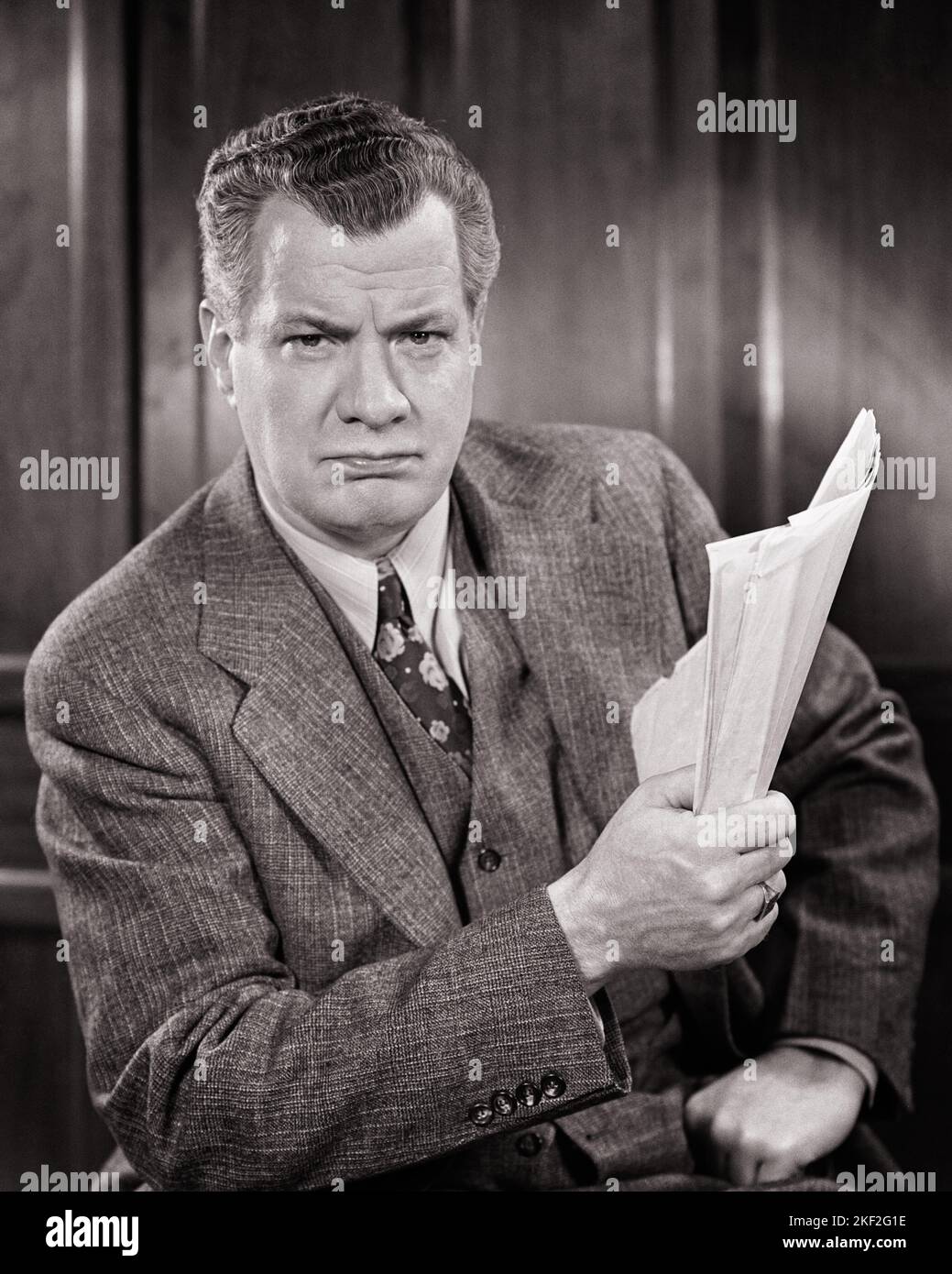 1940S STERN PREOCCUPATO ARRABBIATO UOMO D'AFFARI IN POSSESSO DI DOCUMENTI DI DOCUMENTI CHE INDOSSANO TRE PEZZI VESTITO GUARDANDO LA MACCHINA FOTOGRAFICA - S11172 HAR001 HARS LIFESTYLE MOODY PERSONE DI MEZZA LUNGHEZZA CHE SI PRENDONO CURA DEI MASCHI ESPRESSIONI TURBATE B&W DI MEZZA ETÀ PREOCCUPATA TRISTEZZA UOMO DI MEZZA ETÀ CONTATTO OCCHIO VESTITO E CRAVATTA DOCUMENTI FORZA STRATEGIA POTENTE AUTORITÀ STERN UMORE OCCUPAZIONI CONCETTUALE GLUM LONE MISERABILE NERO E BIANCO ETNICITÀ CAUCASICA HAR001 VECCHIO STILE Foto Stock