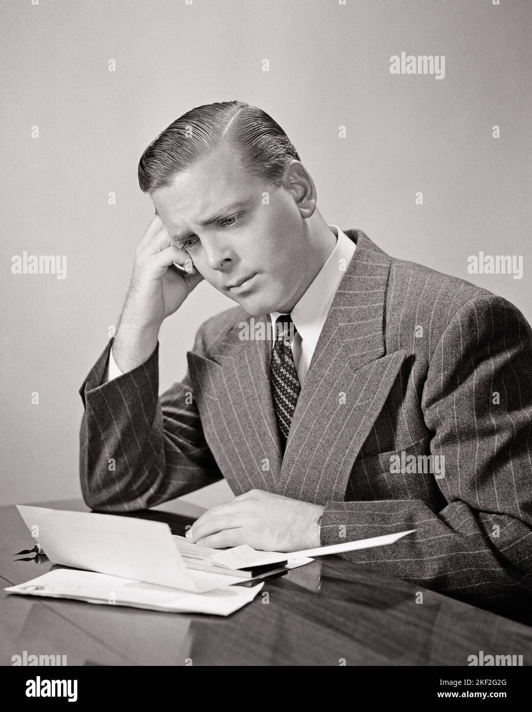 1940S UOMO PREMUROSO CHE INDOSSA UNA TUTA IN PINSTRIPE CHE RIVEDE UN LIBRETTO DI FATTURE SULLA SCRIVANIA CON PENNA IN ATTESA DI DECISIONE DI PAGARE - S11336 HAR001 HARS RIGUARDATO LA MUTA DI TRISTEZZA E LA SCELTA DELLA CRAVATTA RIFLETTENTI L'OCCASIONE DI PENSARE LE OCCUPAZIONI DI UMORE CHE RIFLETTONO IL PONDERING DEL PONDER CONSIDERANO PERSO NEL PENSIERO GLUM ELEGANTE MEDITATE CONTEMPLATIVA KONE MEDITATIVE UOMO MEDIO-ADULTO MEDIO-ADULTO MISERABILE SOLUZIONI NERO E BIANCO ETNICITÀ CAUCASICA CONSIDERANDO HAR001 VECCHIO STILE Foto Stock