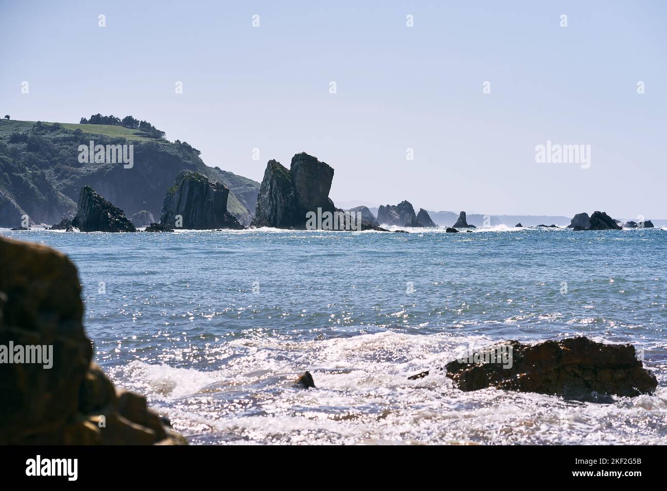 paesaggio del mare cantabrico con grandi rocce vicino alle scogliere verdi che splendono dal sole in un luogo tranquillo e solitario, asturie, spagna Foto Stock