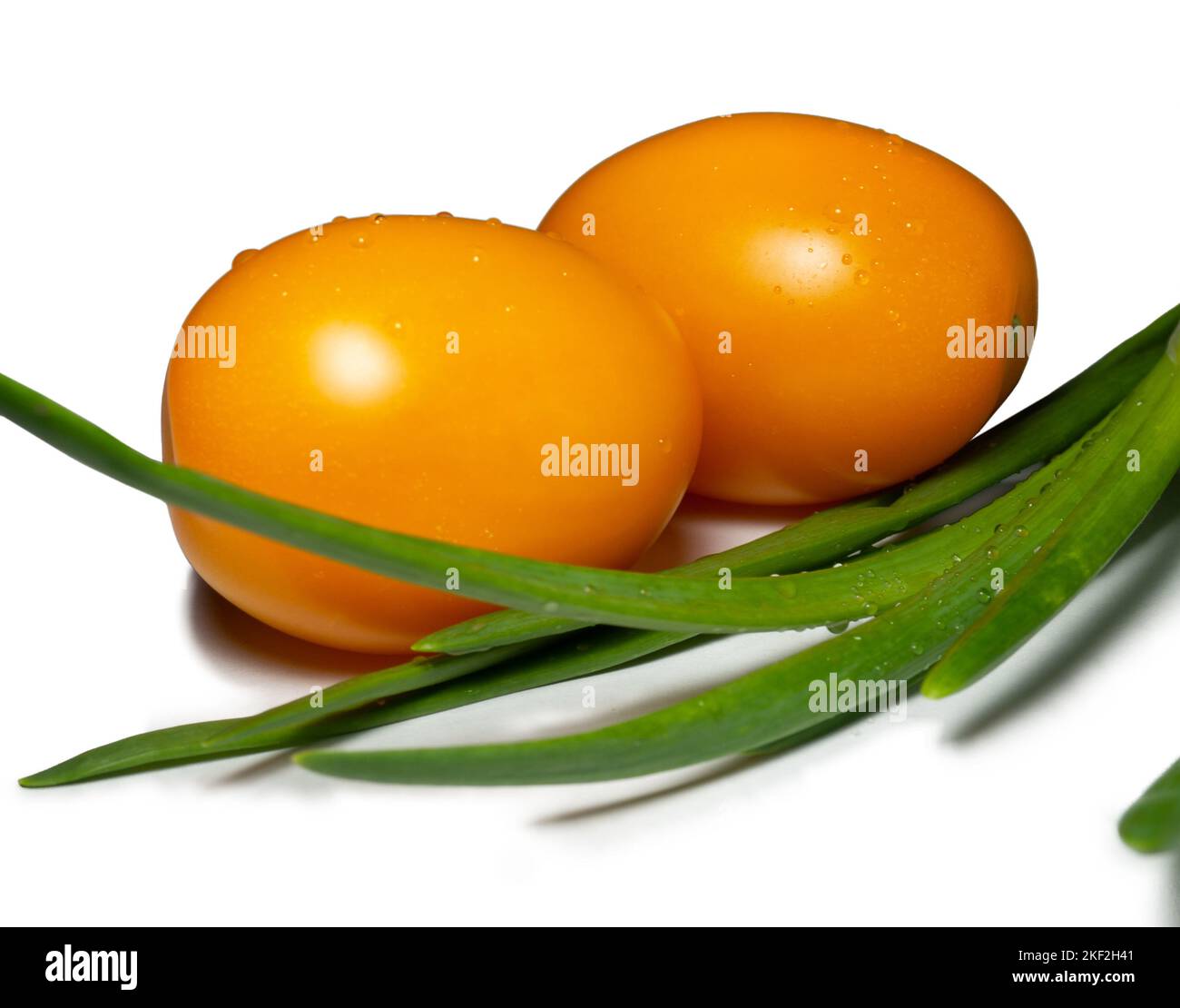 Pomodoro d'arancia e cipolla verde su fondo bianco. Verdura succosa. Varietà di pomodoro. Un bel frutto. Cibo vegetariano. Ingrediente di insalata succosa. o Foto Stock