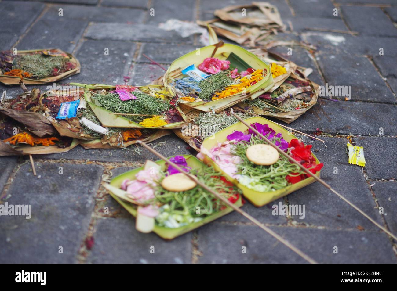 Offerte indù di petali di fiori, cracker, bastoni di caramelle e incenso in pacchi di foglie di banana per le strade di Seminyak — Bali, Indonesia Foto Stock