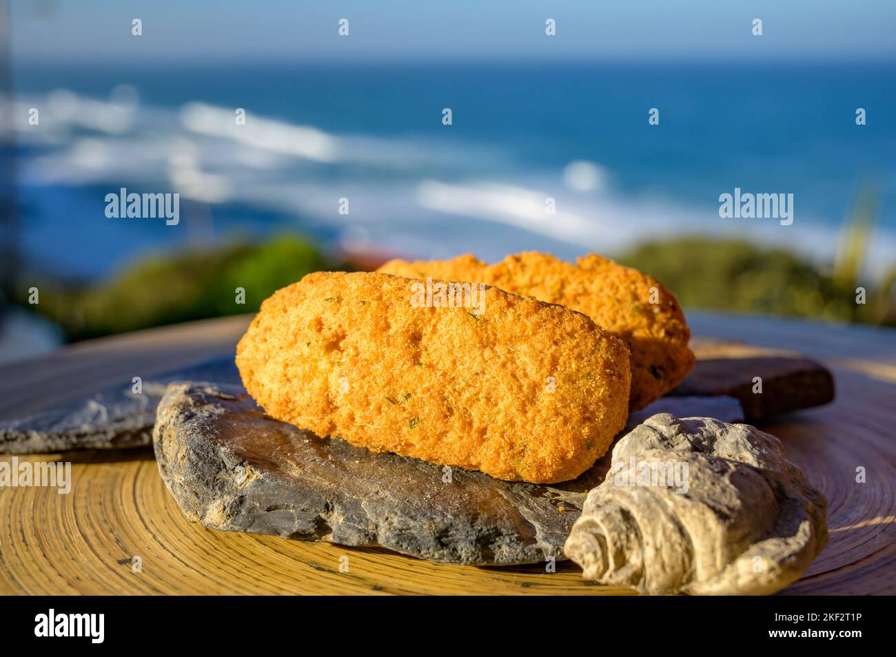 Coccodrillo pastais de bacalhau, spuntini tradizionali portoghesi serviti all'aperto con vista sull'oceano Atlantico blu vicino a Sintra nella zona di Lisbona, P Foto Stock