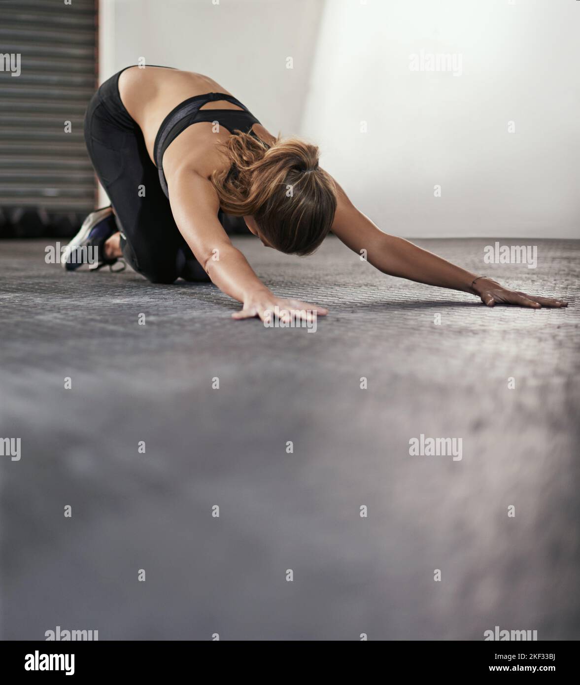 Stretching fuori tutti i suoi muscoli. Una giovane donna che fa esercizi di stretching in palestra. Foto Stock