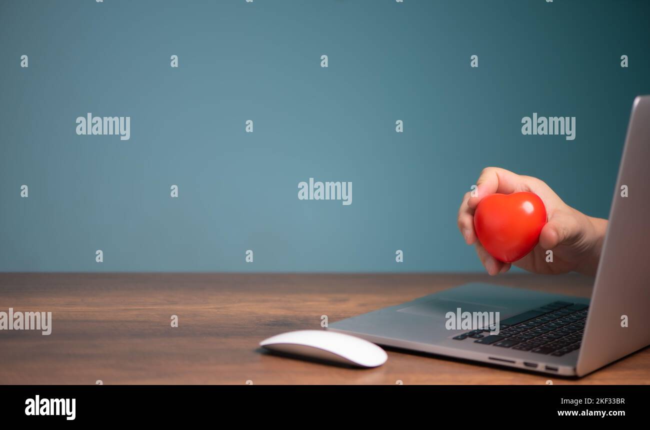 Bastone cuore rosso da uno schermo del computer portatile, dando, donazione, assicurazione, amore chat online dating concetto. Foto Stock