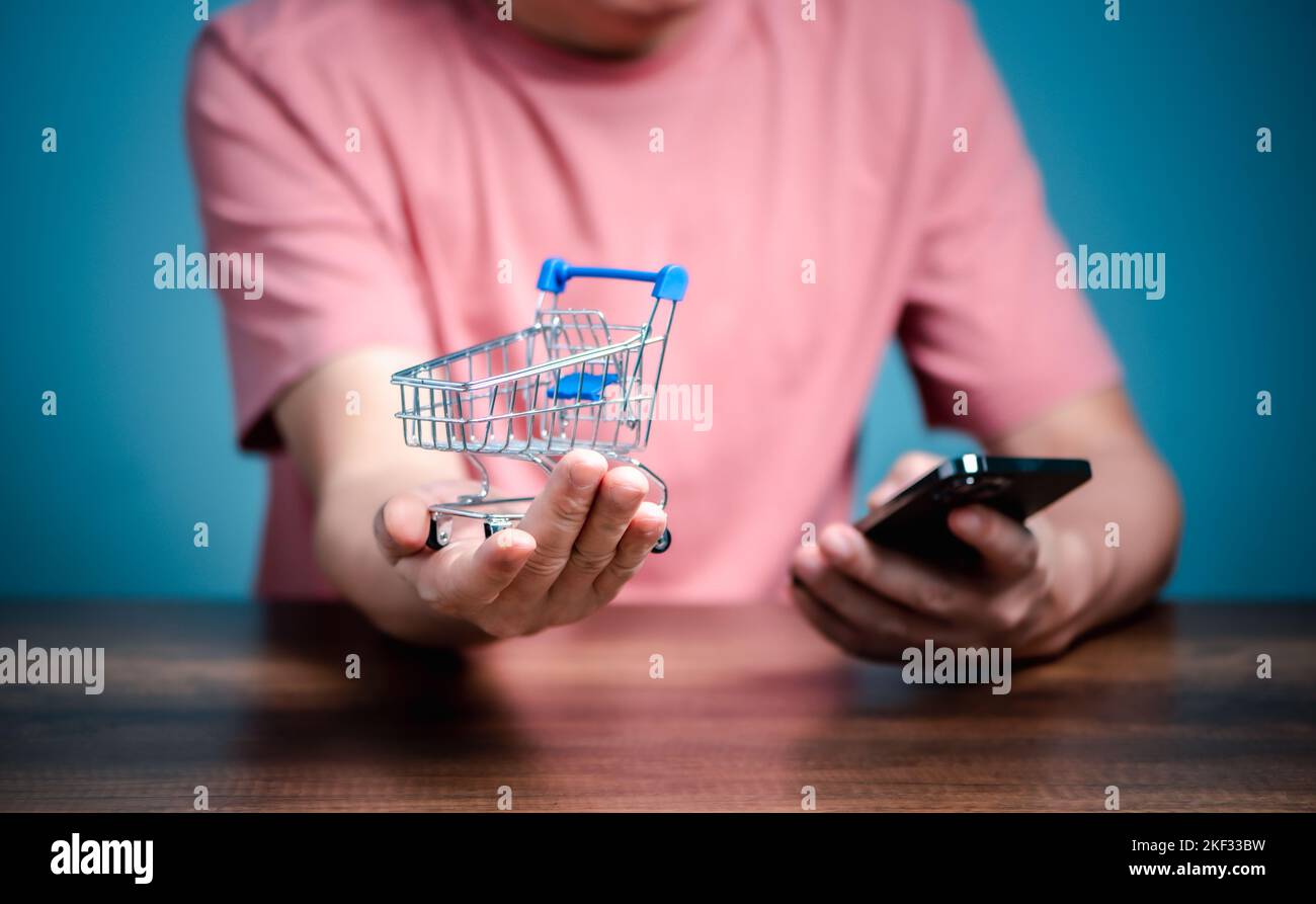 Shopping online con il carrello, l'uomo che utilizza il telefono cellulare acquistare cose sul negozio di pagine web. Foto Stock