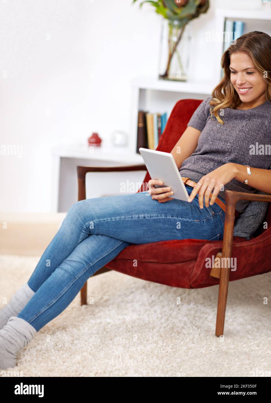 Rilassarsi con un po' di intrattenimento online. Una giovane donna che usa il suo tablet digitale a casa. Foto Stock