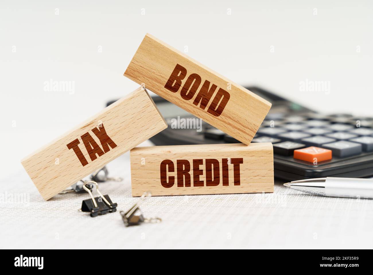 Business ed Economia. Sul tavolo c'è una penna, una calcolatrice e piccoli blocchi di legno con l'iscrizione - Bond Tax Credit Foto Stock