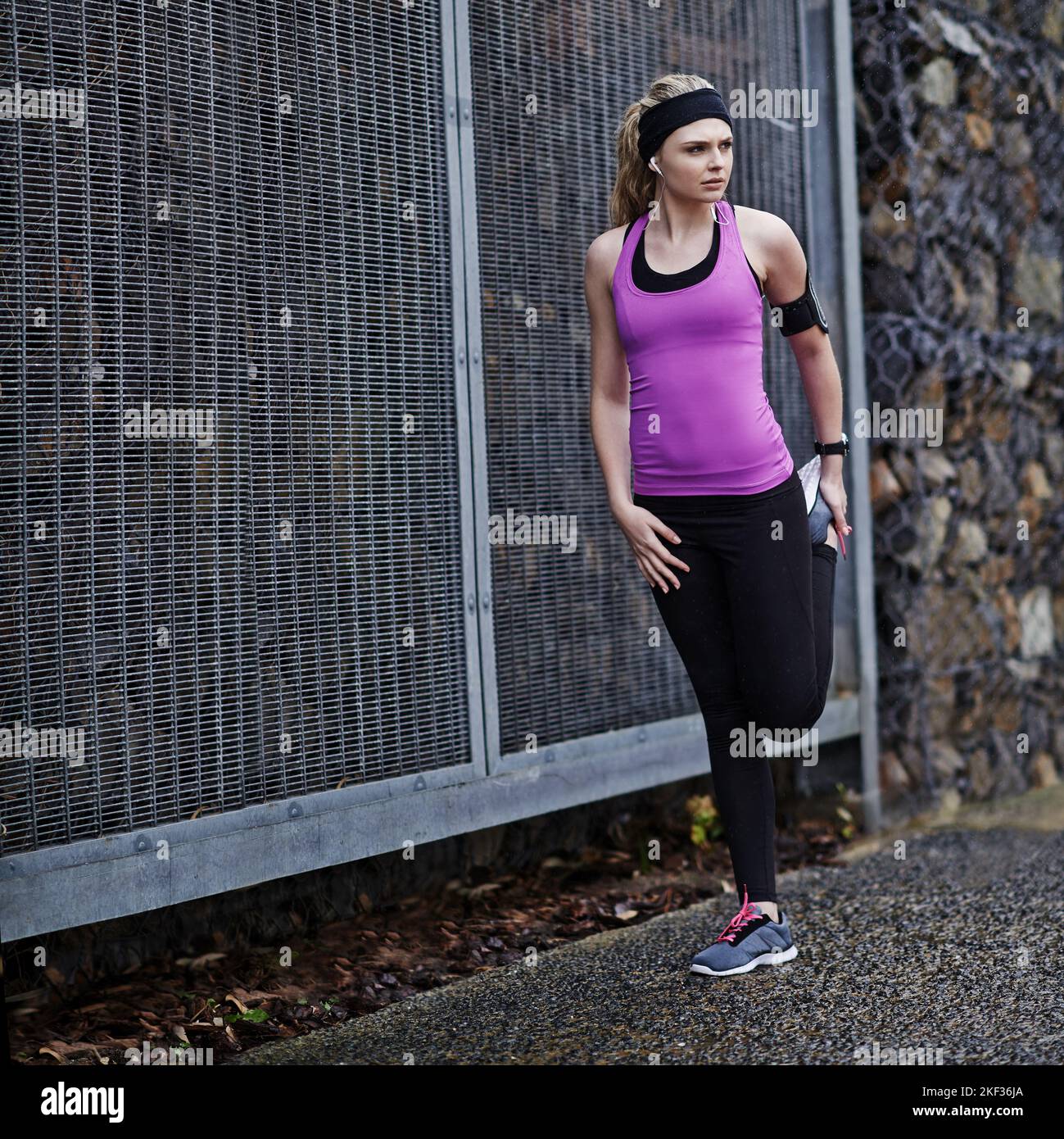 Focalizzata e pronta a correre. Una giovane donna che si allunga le gambe prima di una corsa. Foto Stock