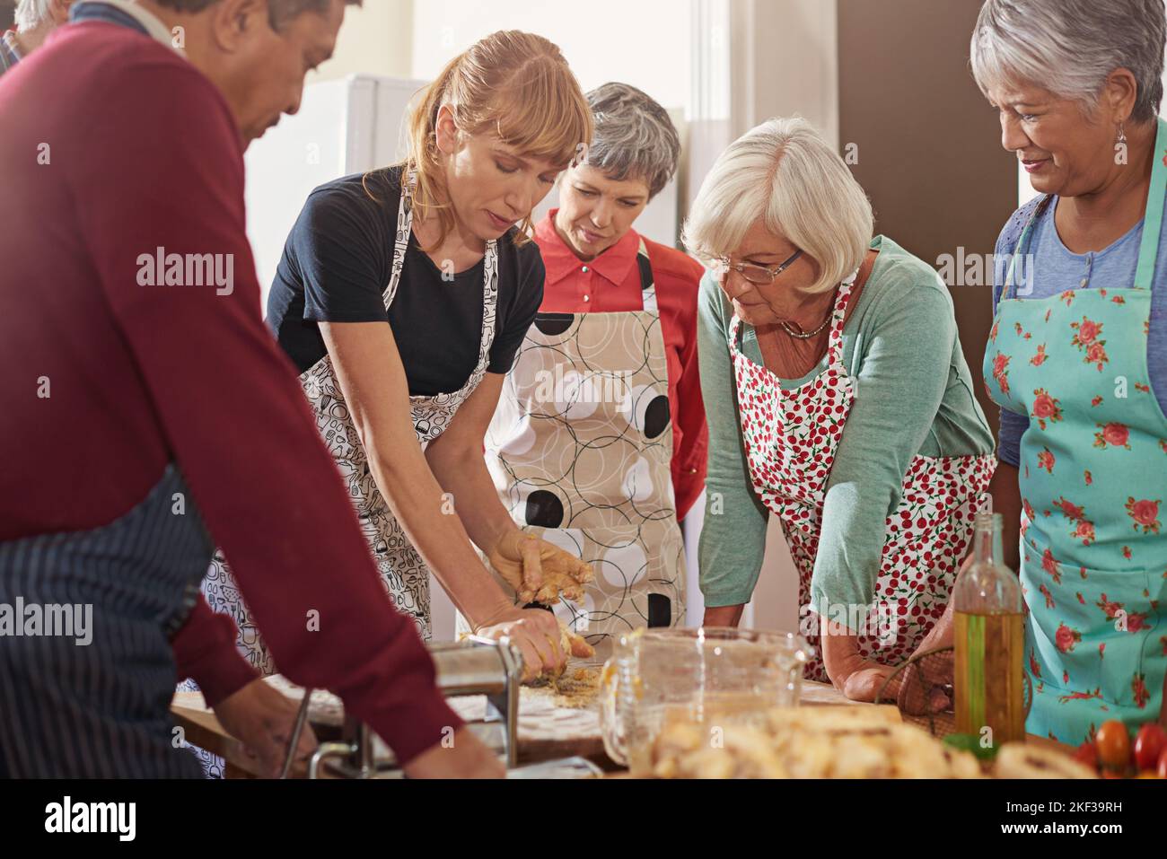 Mostrare loro come tagliare il loro tempo di cucina a metà. Un gruppo di anziani che frequentano una lezione di cucina. Foto Stock
