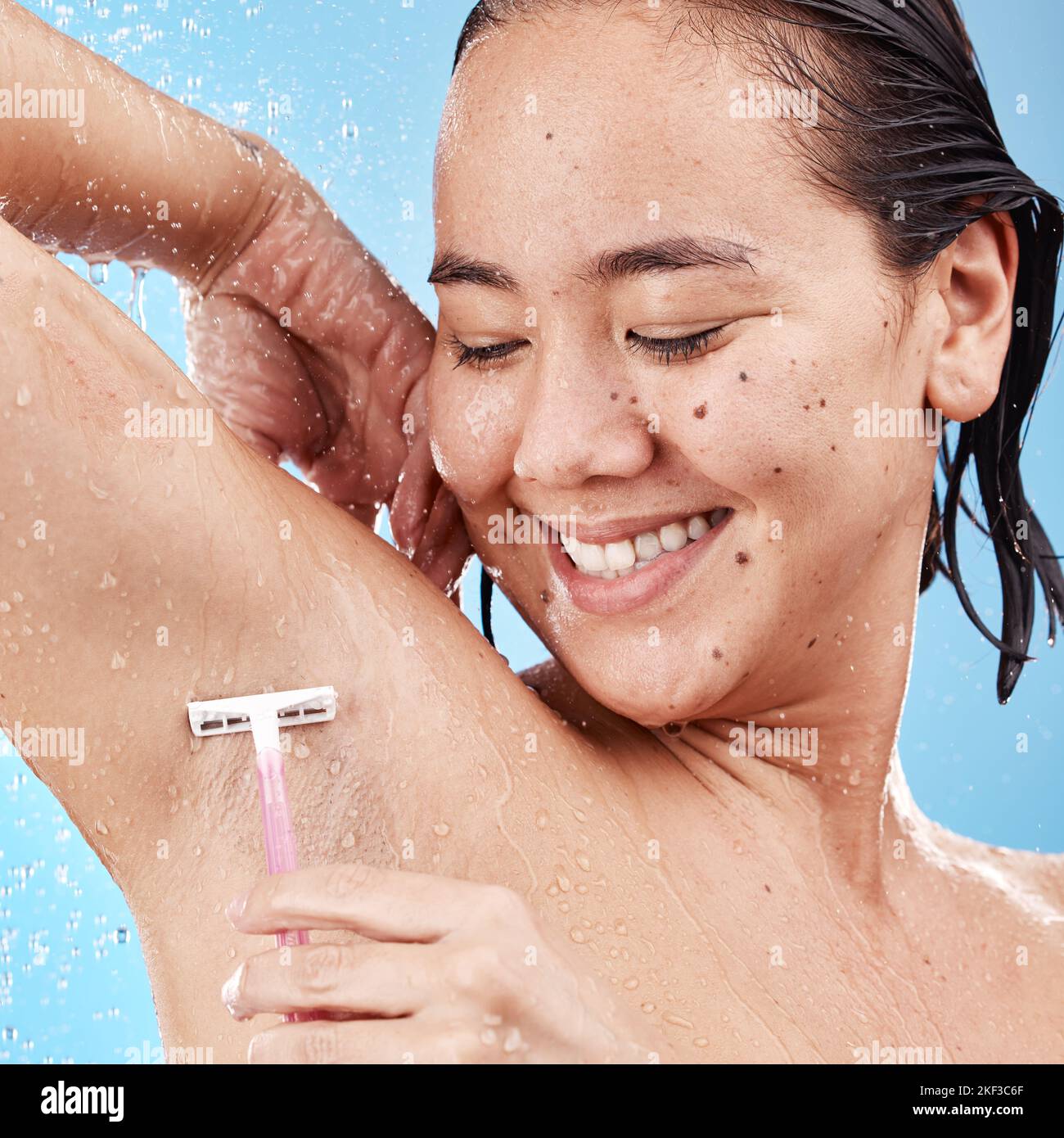 Doccia, donna barba ascella con rasoio e bellezza pulita con acqua e igiene per la cura del corpo su sfondo blu studio. Modello asiatico felice, sano Foto Stock
