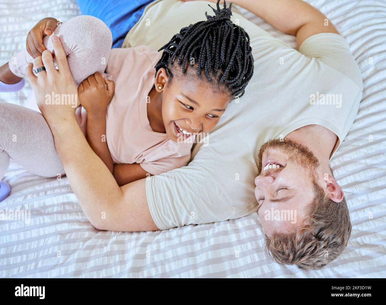 Adozione, gioco e padre con la ragazza sul letto al mattino con un sorriso per felice nella loro casa di famiglia. Famiglia, amore e papà giocando con il suo bambino Foto Stock