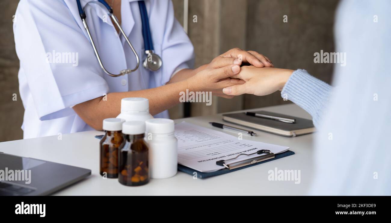 Dottore che dà speranza. Primo piano immagine di una giovane medico femminile che si appoggia in avanti a una donna anziana sorridente che tiene la mano nelle palme. Donna custode Foto Stock