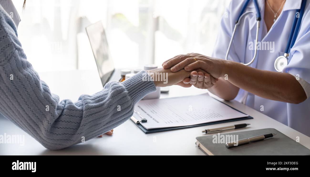 Dottore che dà speranza. Primo piano immagine di una giovane medico femminile che si appoggia in avanti a una donna anziana sorridente che tiene la mano nelle palme. Donna custode Foto Stock