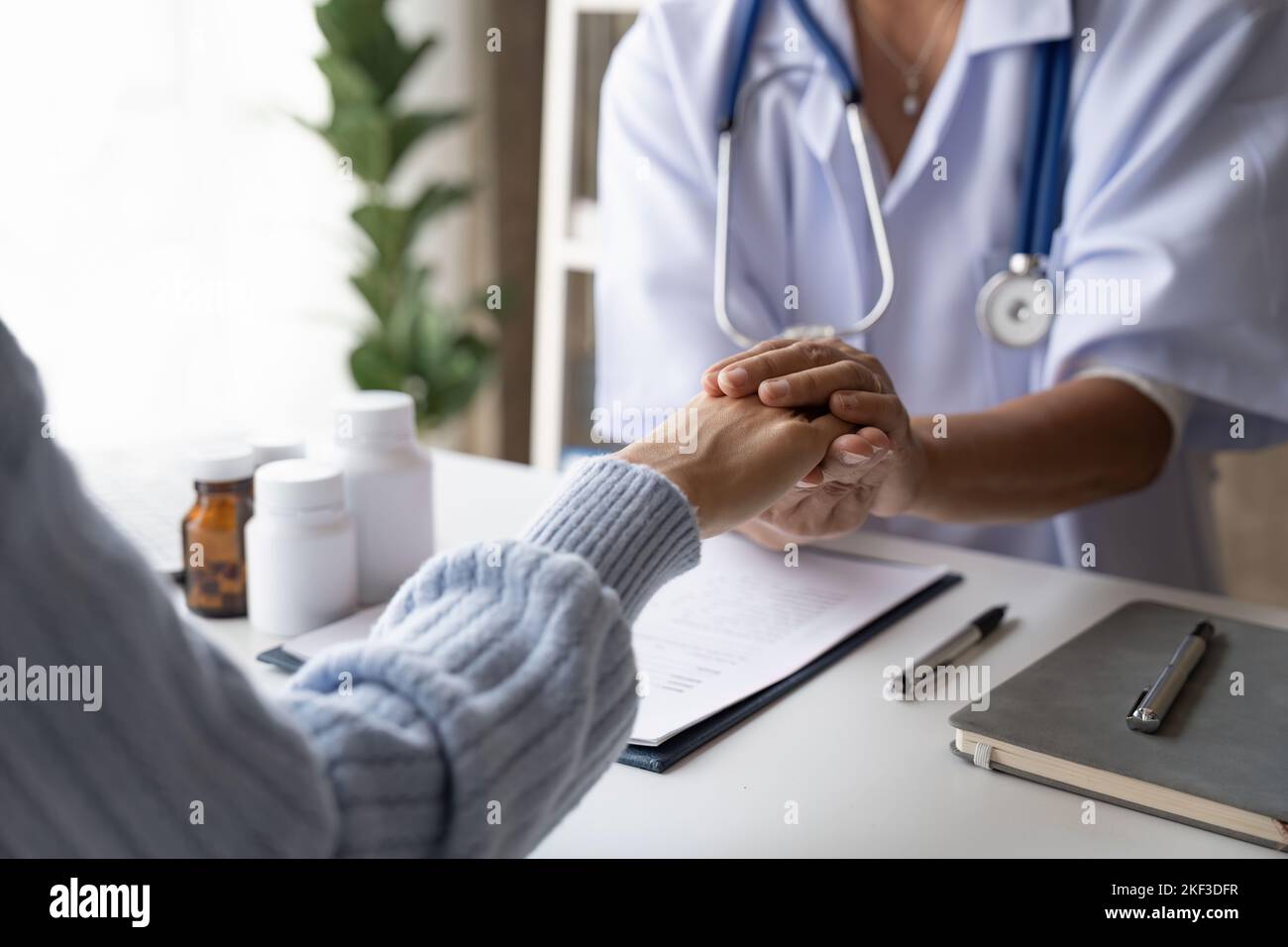 Dottore che dà speranza. Primo piano immagine di una giovane medico femminile che si appoggia in avanti a una donna anziana sorridente che tiene la mano nelle palme. Donna custode Foto Stock