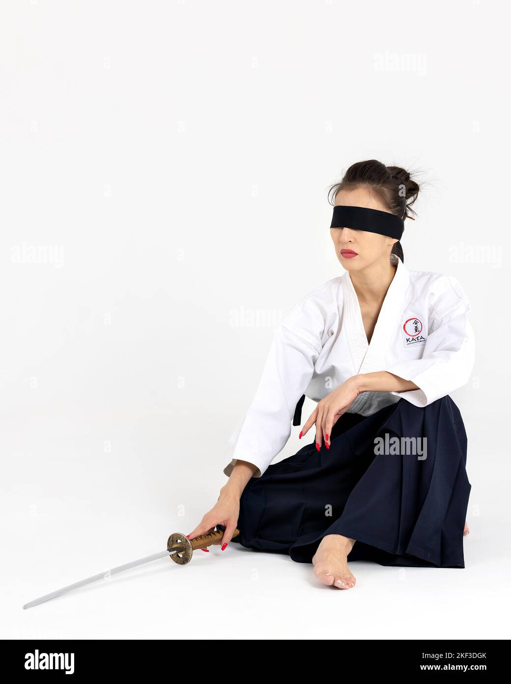 Aikido padrona in kimono tradizionale samurai hakama con cintura nera con spada, katana su sfondo bianco. Stile di vita sano e concetto di sport. Foto Stock