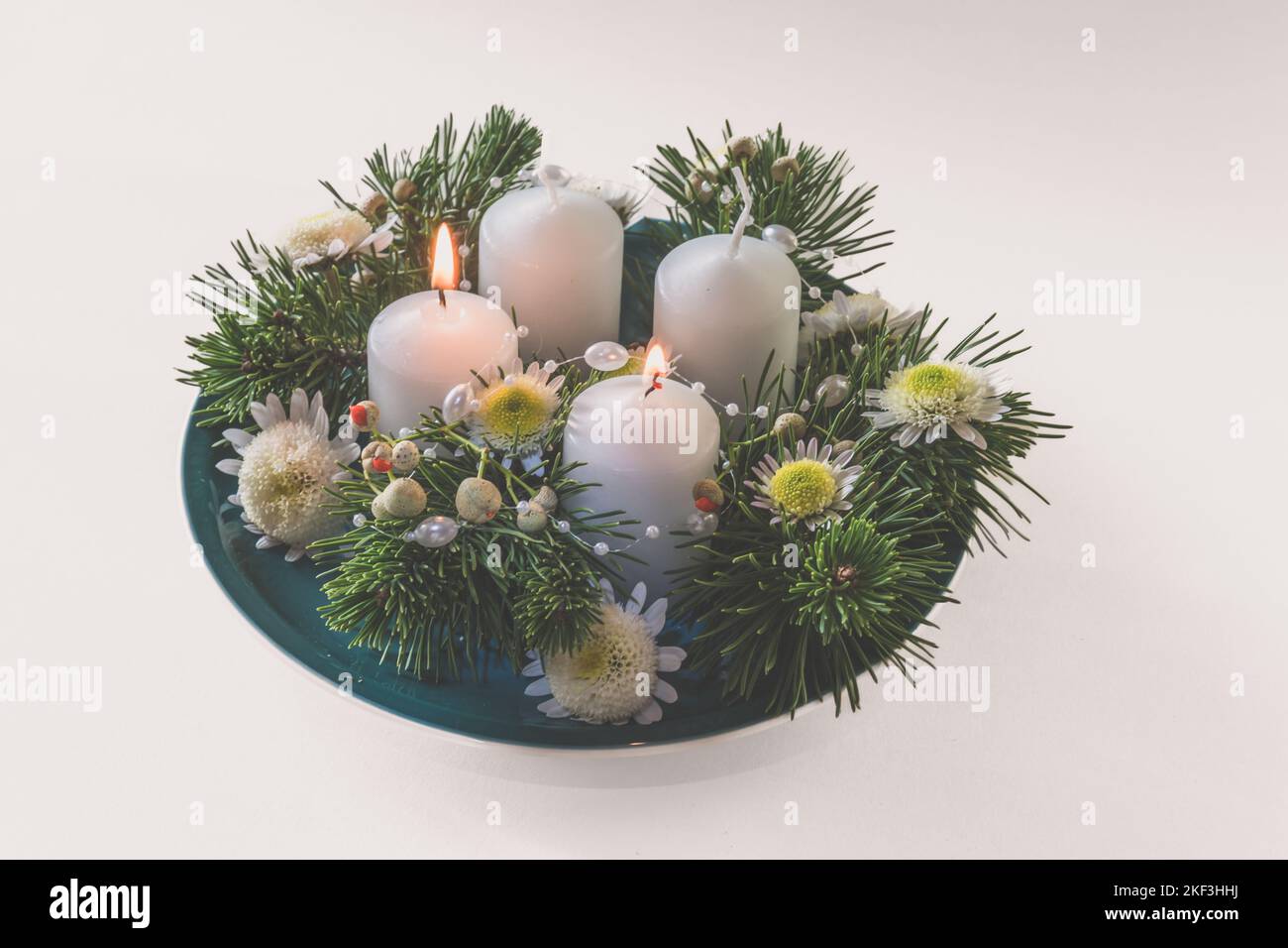 4 candele bianche d'avvento in corona cristiana religiosa tradizionale decorata con abete verde e fiori Foto Stock