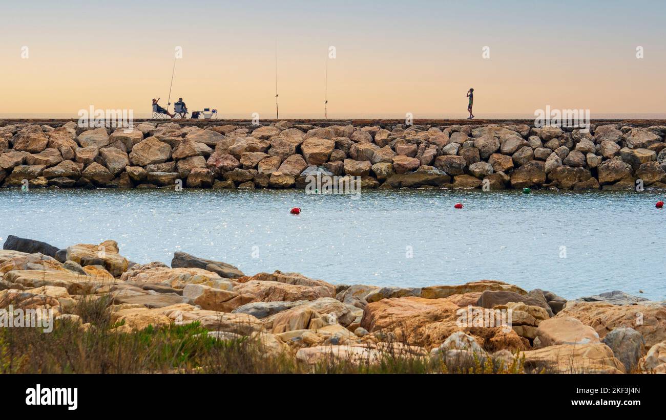 Pescatori ricreativi con le loro canne da pesca sul molo di pietra a Marbella. Foto Stock