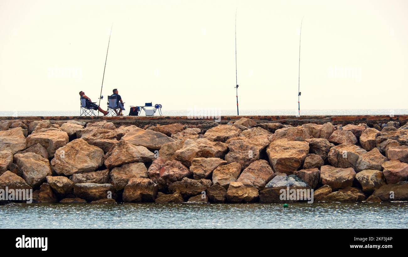 Pescatori ricreativi con le loro canne da pesca sul molo di pietra a Marbella. Foto Stock