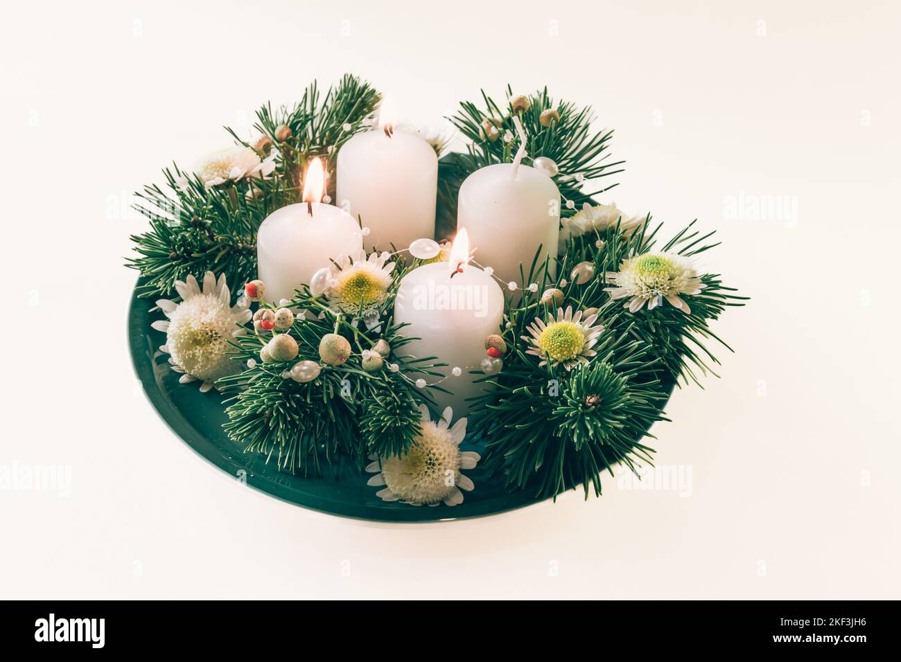 4 candele bianche d'avvento in corona cristiana religiosa tradizionale decorata con abete verde e fiori Foto Stock