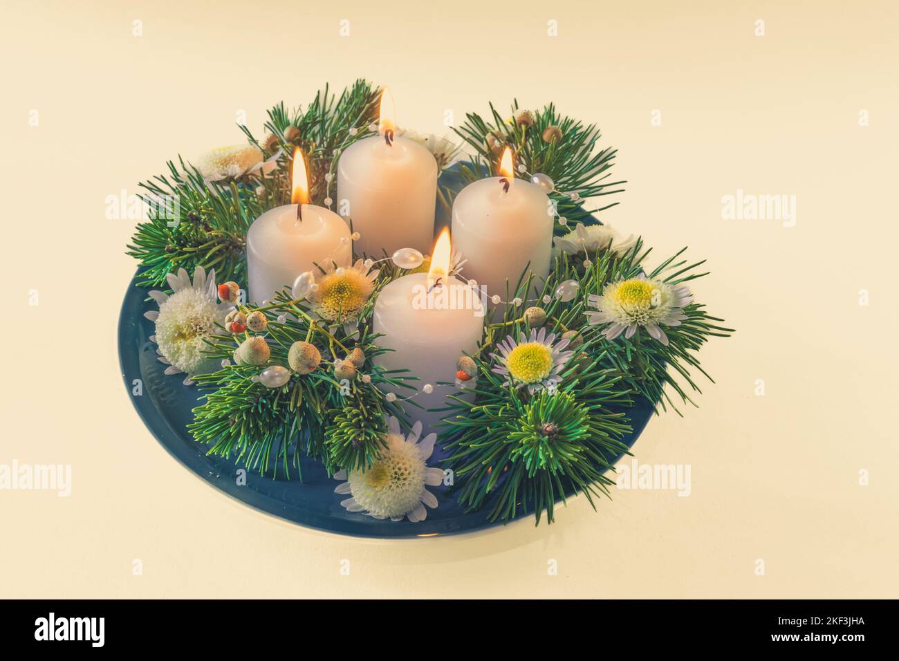 4 candele bianche d'avvento in corona cristiana religiosa tradizionale decorata con abete verde e fiori Foto Stock