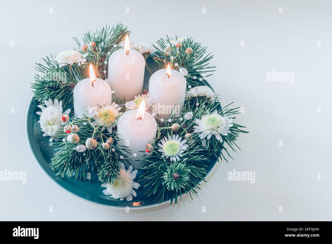 4 candele bianche d'avvento in corona cristiana religiosa tradizionale decorata con abete verde e fiori Foto Stock