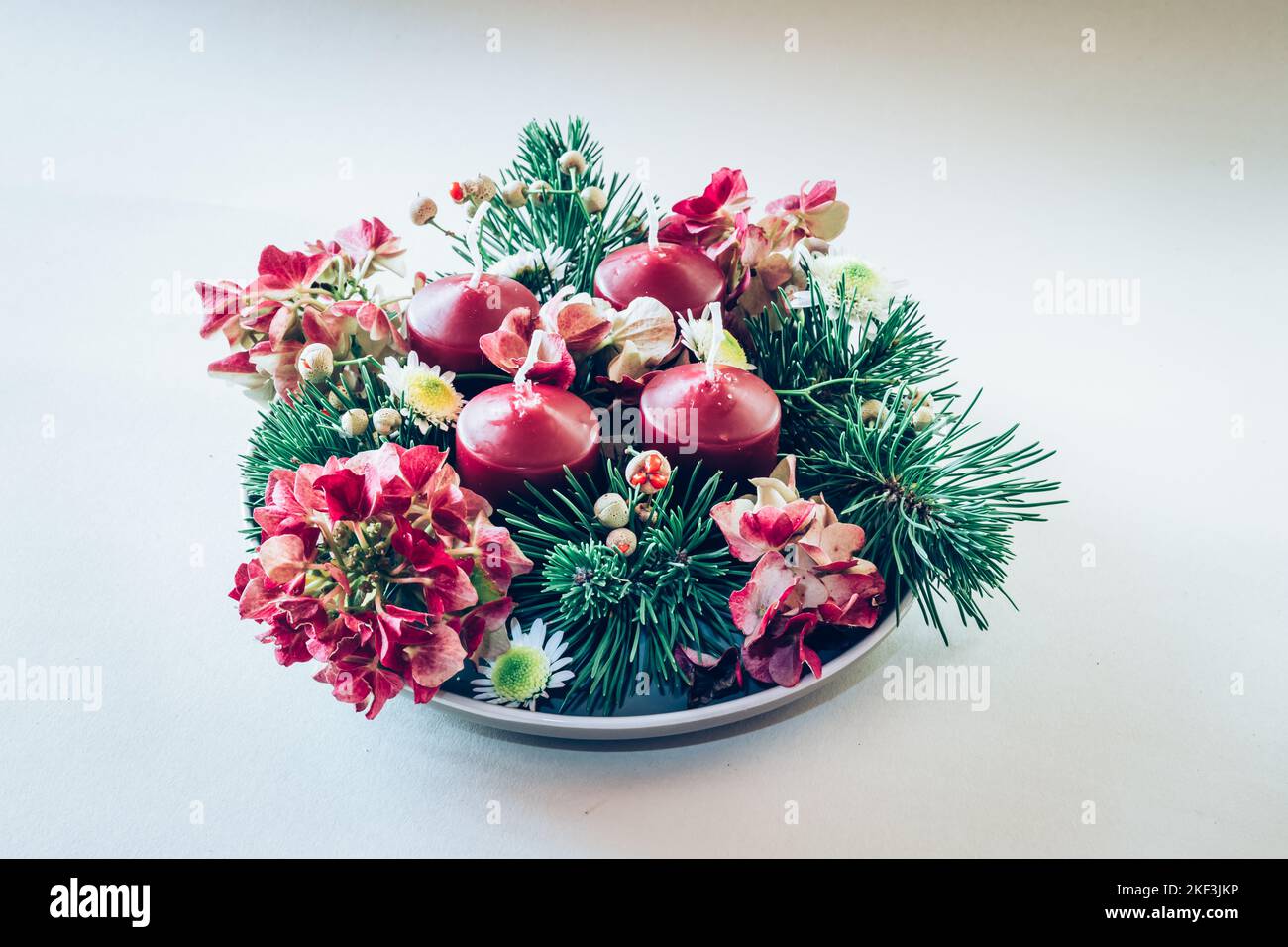 4 candele rosse d'avvento in corona cristiana religiosa tradizionale decorata con fiori di abete verde e ortensia Foto Stock