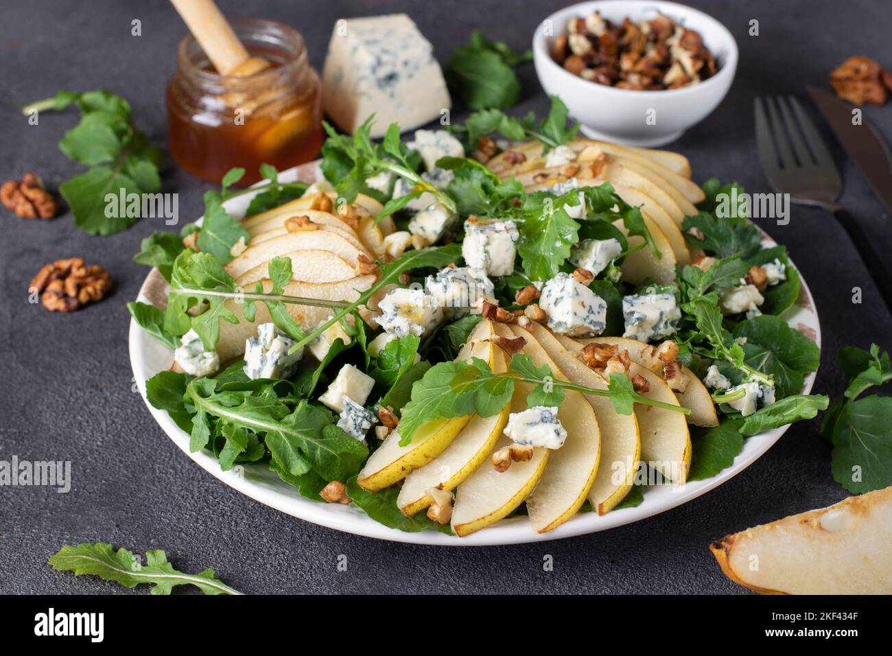 Insalata con rucola, pera, formaggio blu dor, miele e noci in piatto su tavolo grigio. Cibo vegano Foto Stock