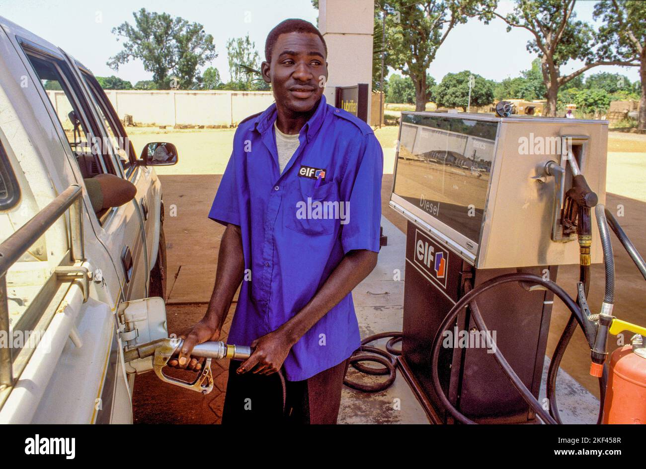 Burkina Faso, Fada dipendente di una stazione di gazoline che riempie un'auto. Foto Stock