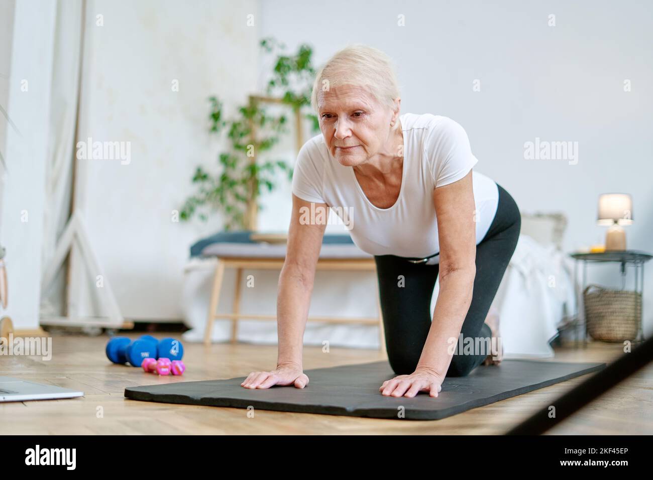 donna anziana che esegue l'istruzione fisica con un addestratore in linea. Foto Stock