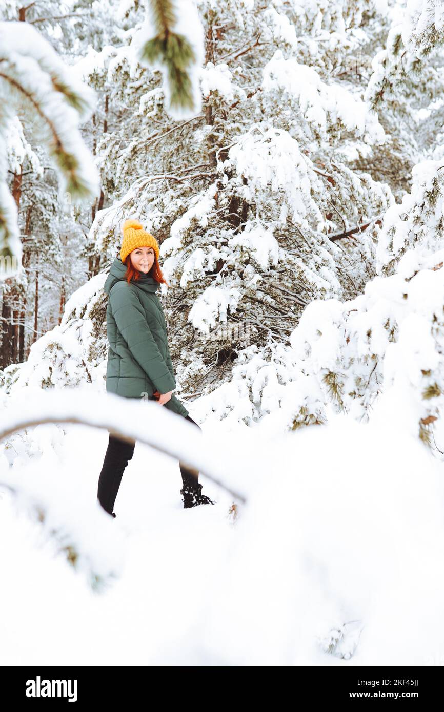 Ragazza allegra in abiti caldi giocando con la neve all'aperto vicino alla bella foresta Foto Stock