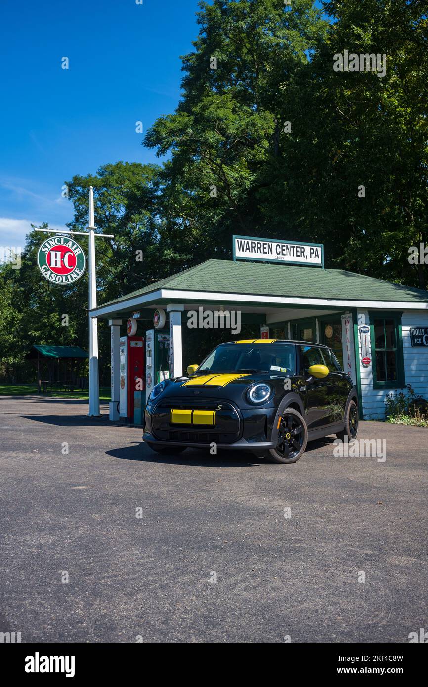 Warren Center, PA, USA - 24 settembre 2022: Un mini Cooper se 2023 nero e giallo, un veicolo elettrico, è fotografato vicino ad una stazione di benzina vintage locate Foto Stock