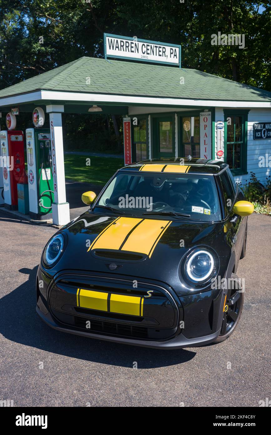 Warren Center, PA, USA - 24 settembre 2022: Un mini Cooper se 2023 nero e giallo, un veicolo elettrico, è fotografato vicino ad una stazione di benzina vintage locate Foto Stock