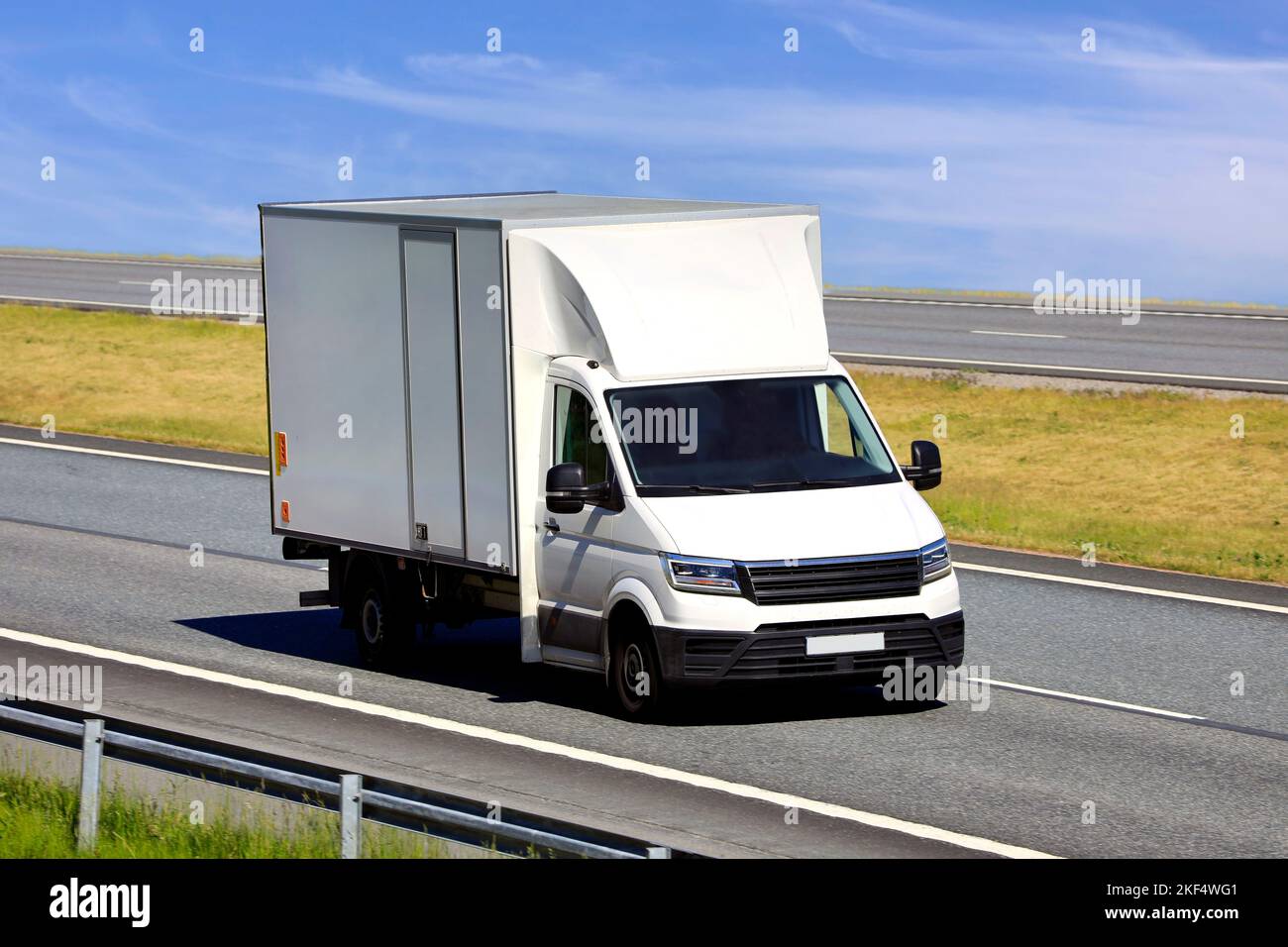 Camion bianco leggero per il trasporto regionale e le consegne a velocità su autostrada in un giorno d'estate. Foto Stock