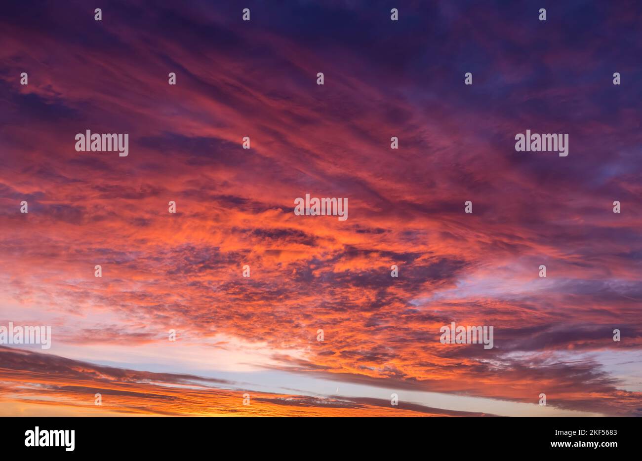 Un cielo all'alba con paesaggio nuvoloso nei toni del magenta, rosa e arancione tenui Foto Stock