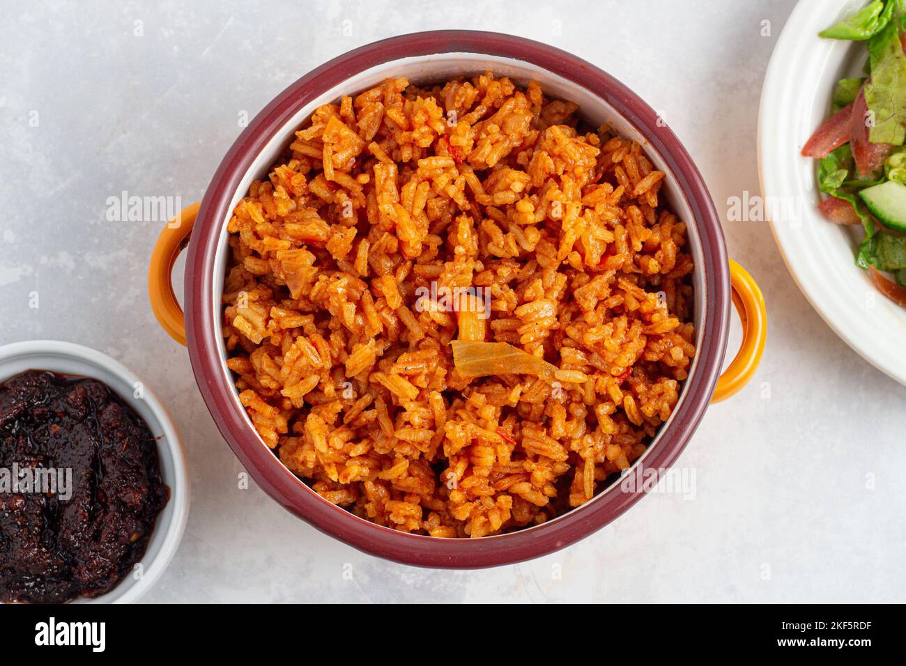 Riso Jollof servito con insalata e Ghana shito Foto Stock
