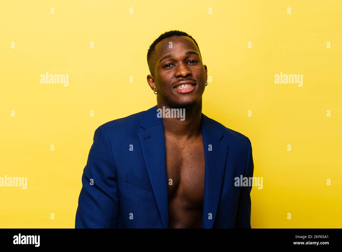 Ragazzo in tuta blu su sfondo giallo. Bell'uomo atletico in giacca sorridente Foto Stock