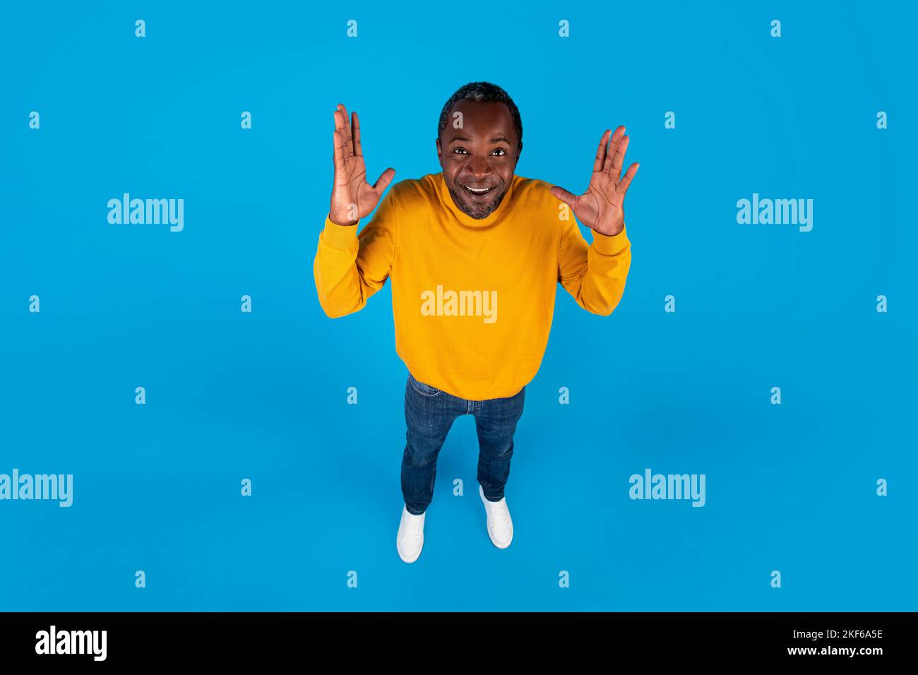 Vista ad angolo alto dell'emotivo uomo nero che alza le mani Foto Stock