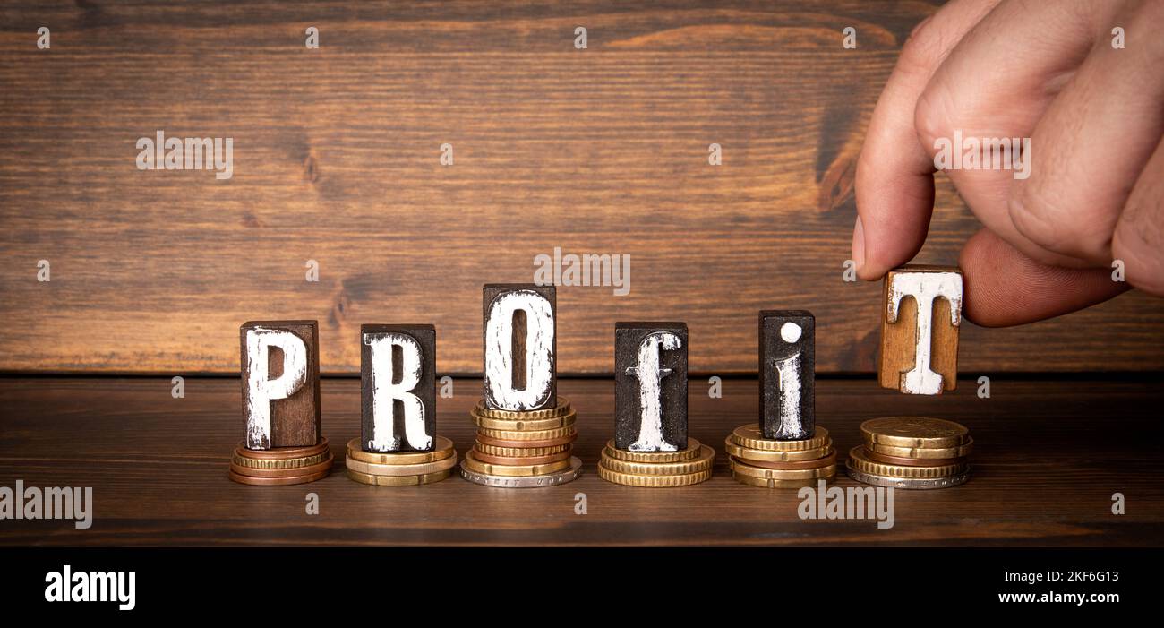 PROFITTO. Cambiare e alfabeto blocchi di lettere su sfondo di legno scuro. Foto Stock