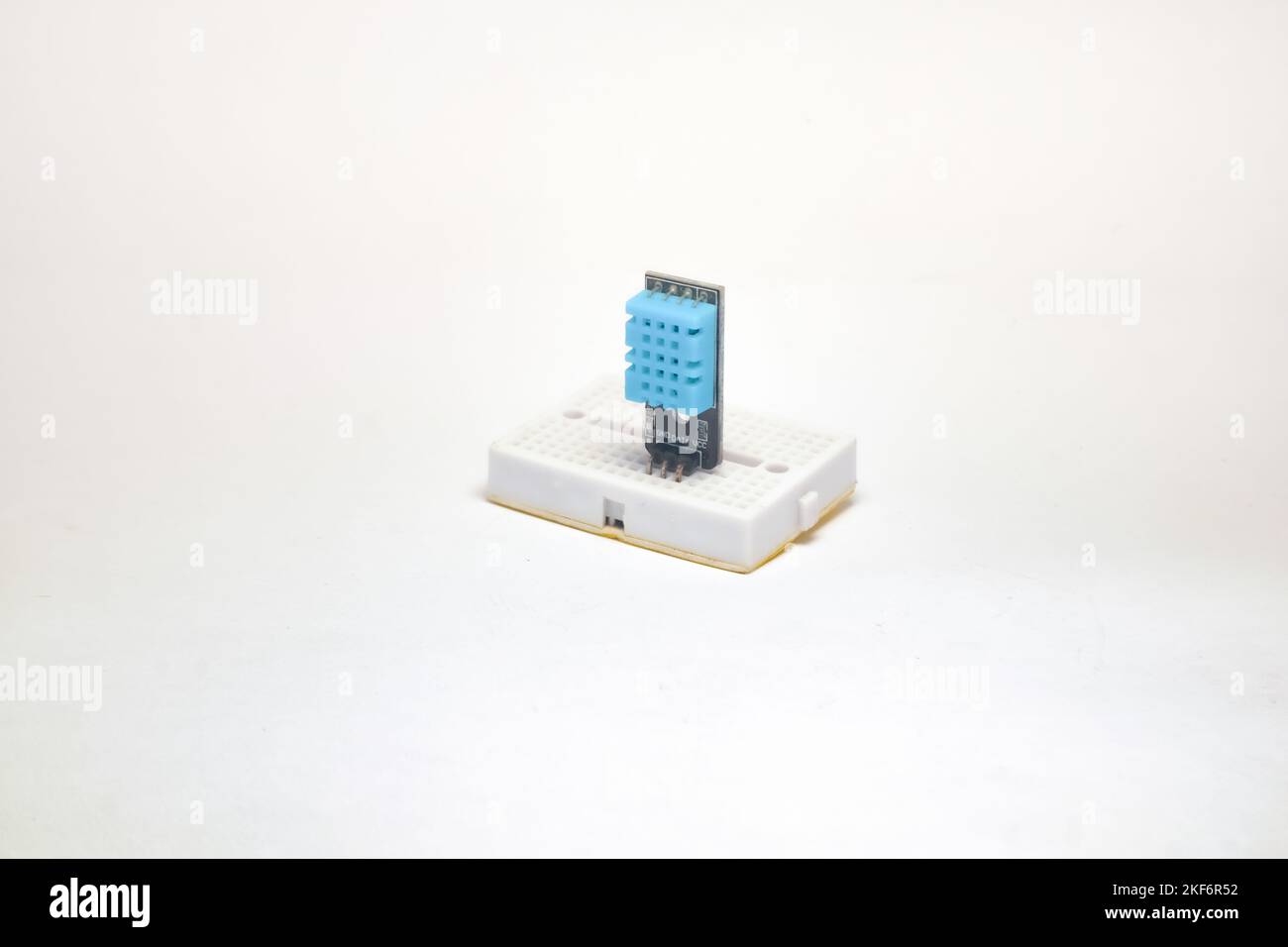 Un sensore DHT11, un sensore di temperatura e umidità, incorporato in una vista laterale della scheda di progetto su sfondo bianco. Foto Stock