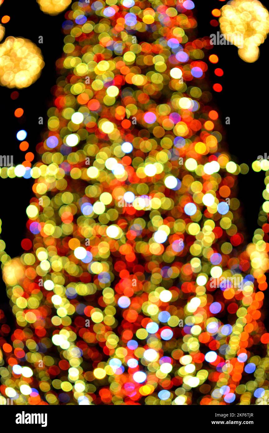 Sfondo sfocato. Bello luminoso e lampeggiante capodanno e decorazione di Natale ghirlande e palle incandescenti per l'albero di Natale che pende all'aperto a nero night.Blurry punti bokeh lampeggiante sfondo Foto Stock