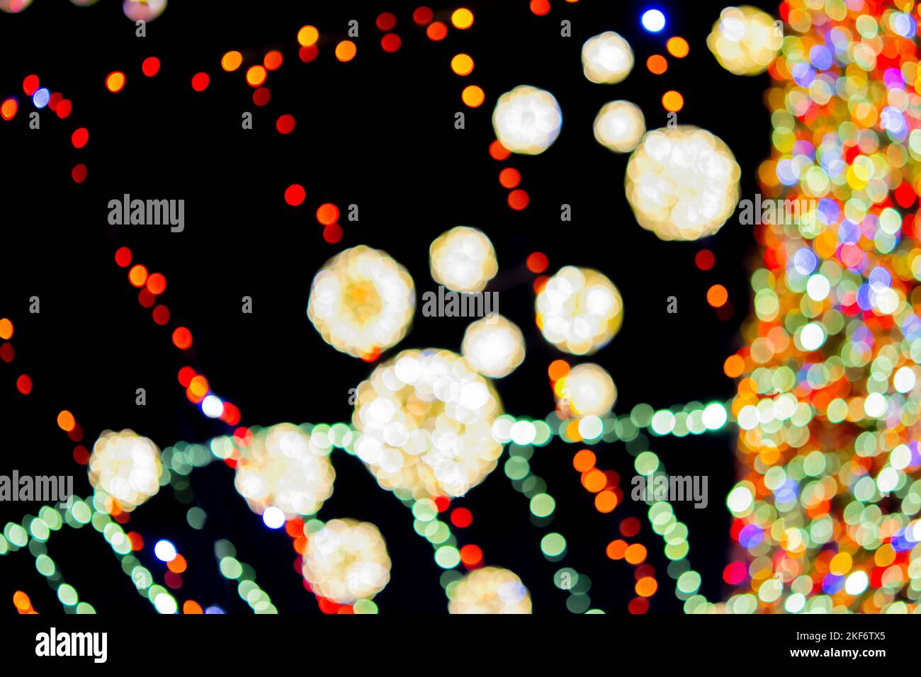 Sfondo sfocato. Bello luminoso e lampeggiante capodanno e decorazione di Natale ghirlande e palle incandescenti per l'albero di Natale che pende all'aperto a nero night.Blurry punti bokeh lampeggiante sfondo Foto Stock