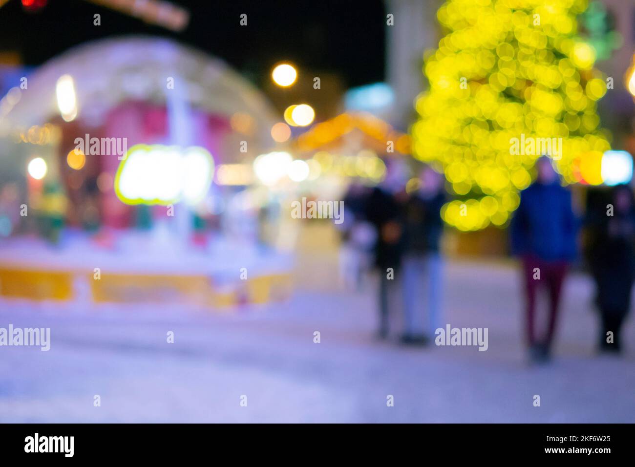 Sfondo sfocato. Albero di Natale, luci decorate, edificio, sagome sfocate di persone che camminano piazza della città durante la notte d'inverno. Bello Capodanno e Natale vacanza sfondo sfocato Foto Stock